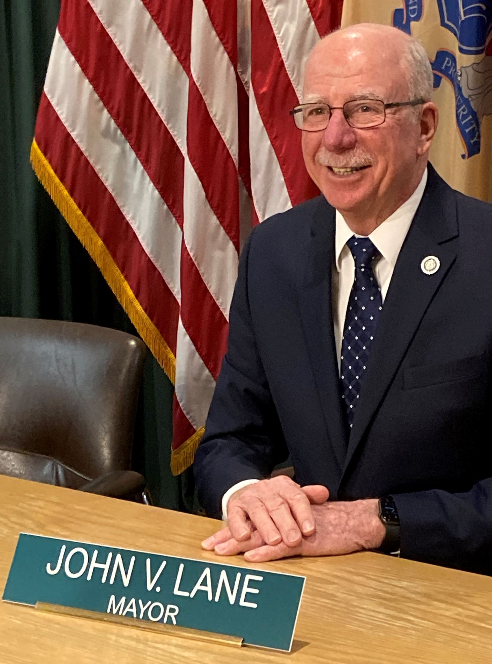 Mayor John V Lane sitting by US Flag